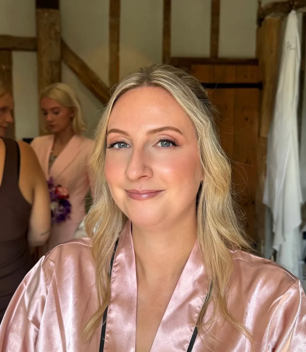 Bride in a satin robe with soft glam makeup, ready for her wedding