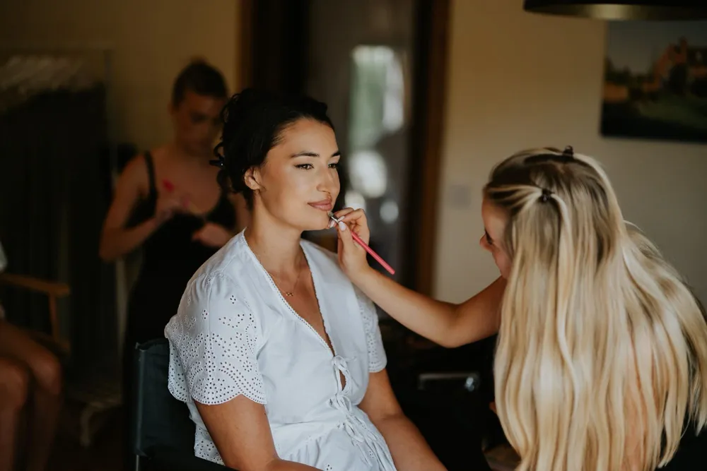 Lucy applying lipstick to a bride on her wedding morning