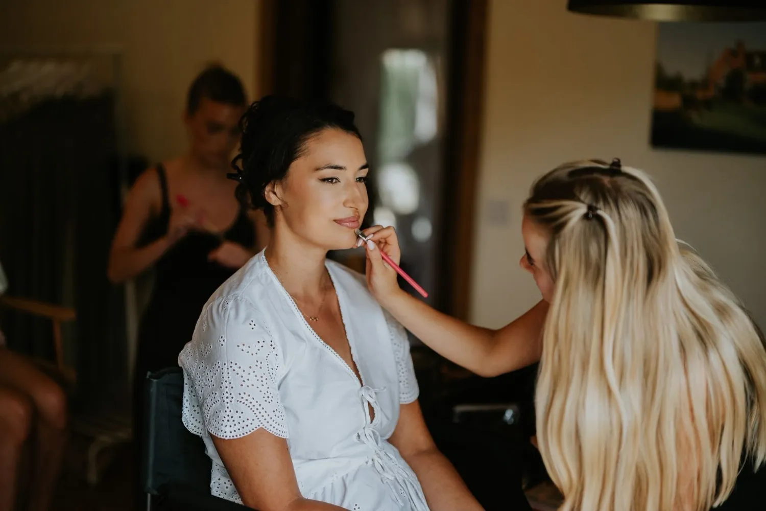Lucy applying lipstick to a bride on her wedding morning